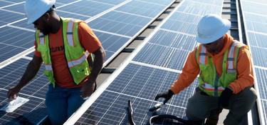 Two men working on a roof installing solar panels