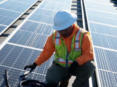 Two men working on a roof installing solar panels