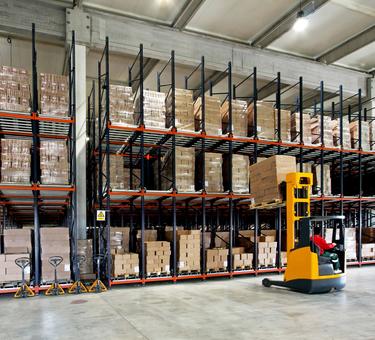 Forklift placing product on a rack in a warehouse